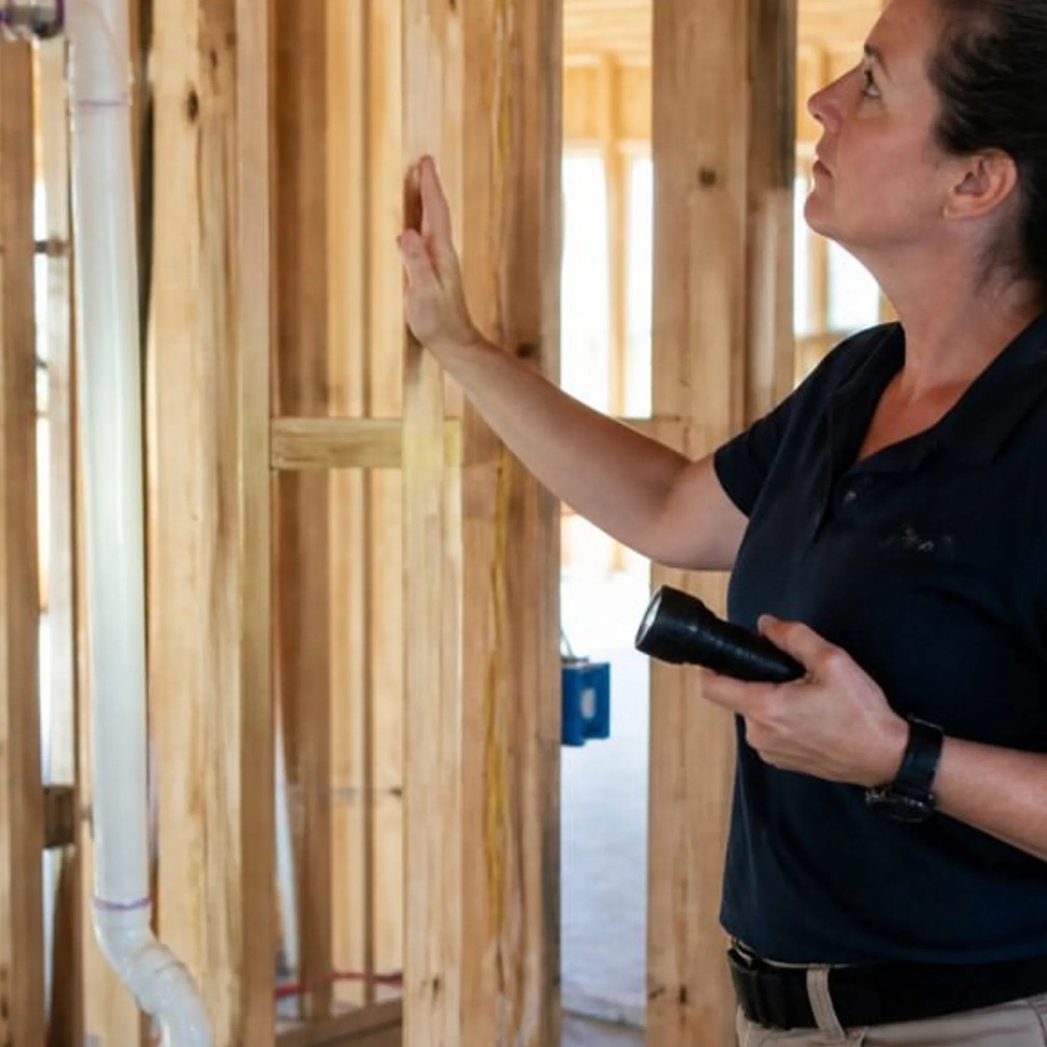 inspector examining exposed plumbing framing